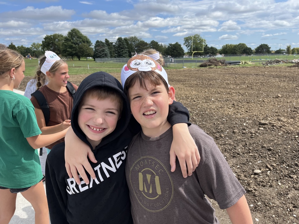 Two boys smiling for a picture with their hands around each other.