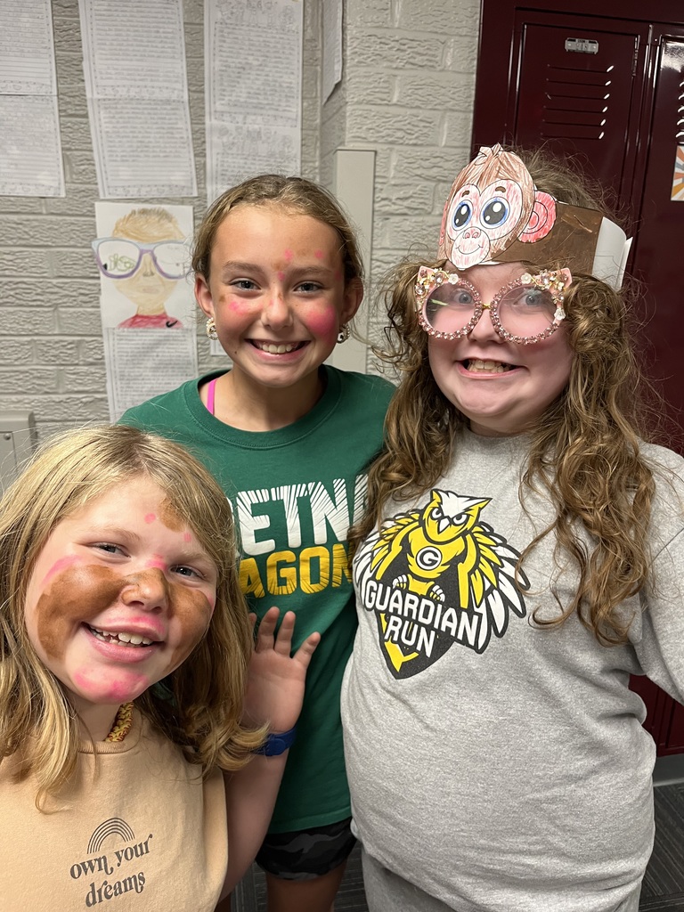 Three girls smiling with two of them having face paint on their face.