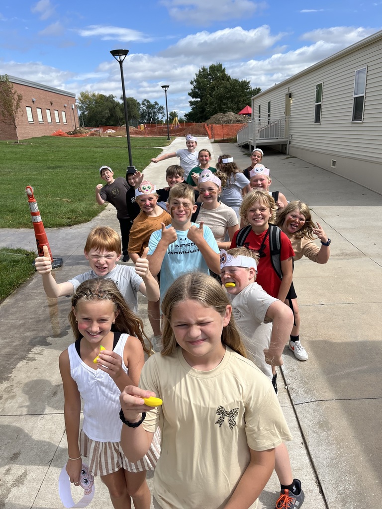 Group of students smiling with some holding thumbs up while others have small bananas in their hands.