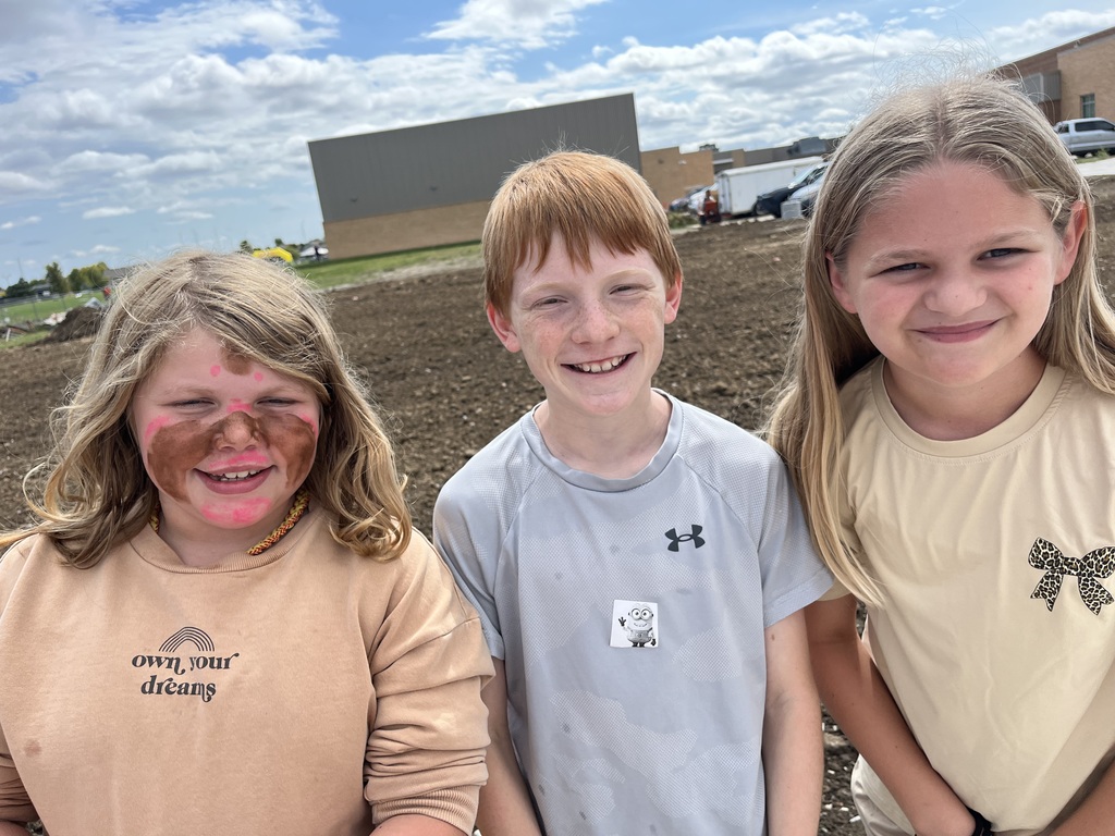 Two girls and a boy smiling while posing for a picture.