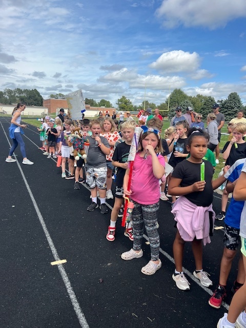 Group of students standing on a track eating popsicles.