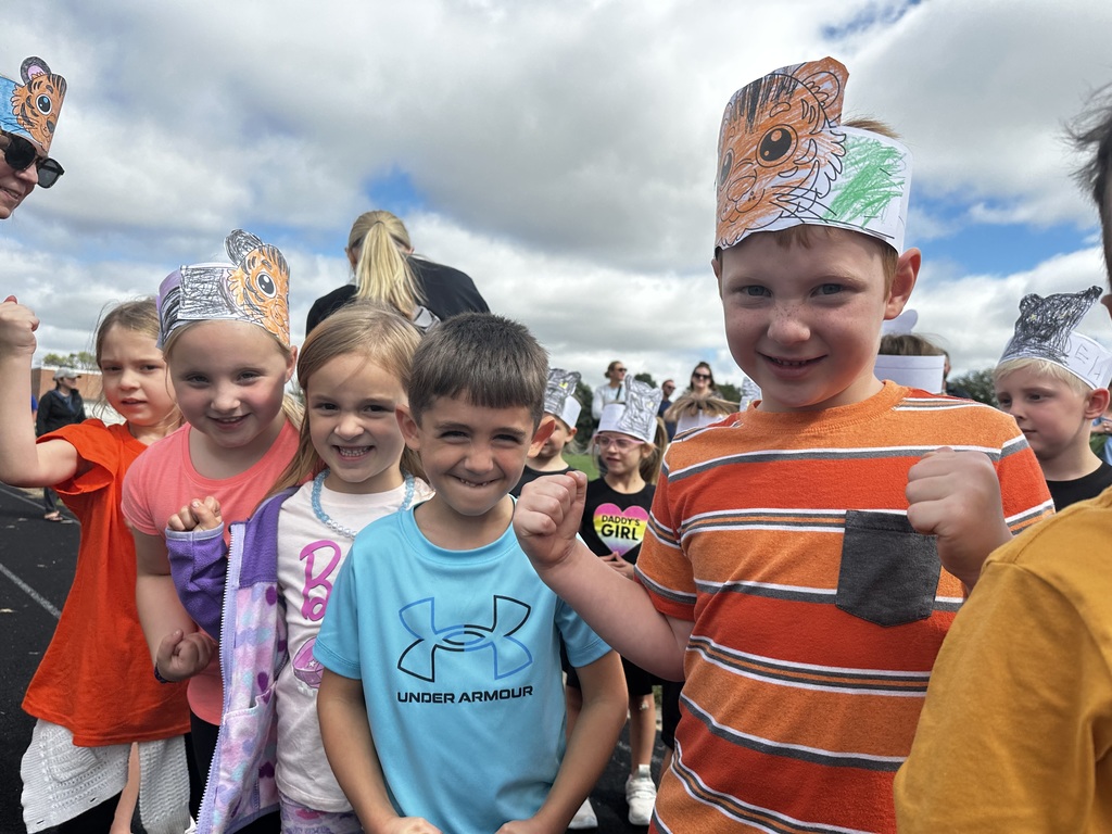 Five students smiling for a photo with two wearing paper tiger headbands.