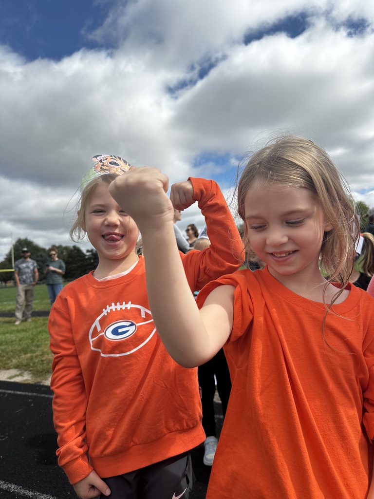 Two girls smiling holding their arms up to show their muscles.