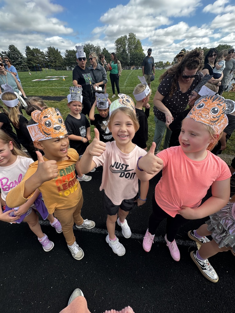 Group of students with tiger paper headbands showing thumbs up on a track.