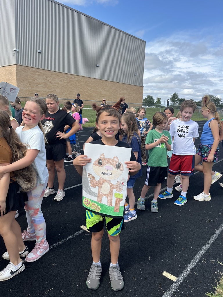 A student wearing squirrel ears while holding a squirrel poster with other students standing in background.