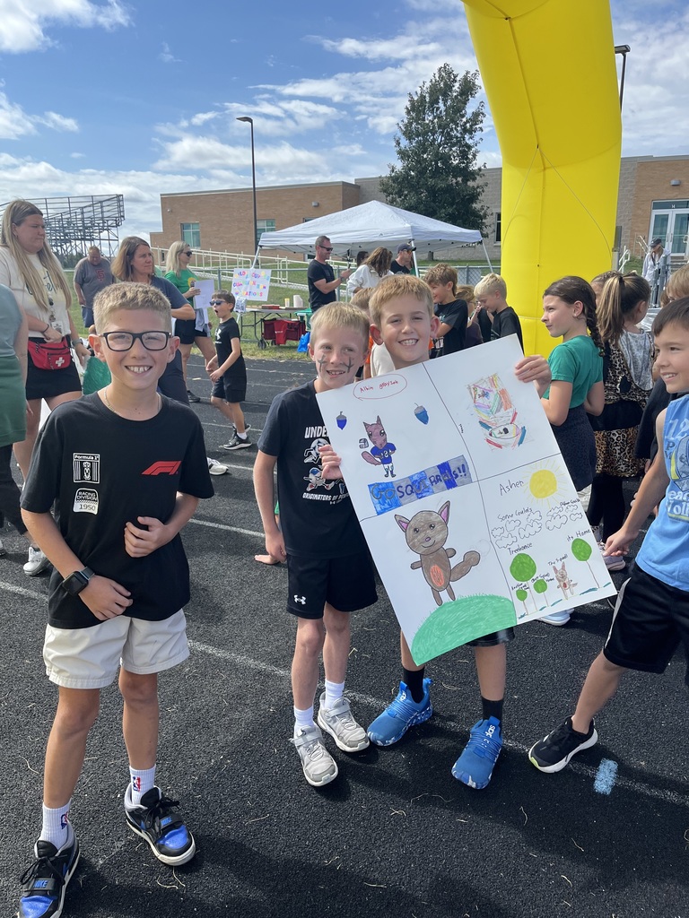 A group of boys wearing black holding a poster with drawn squirrels.