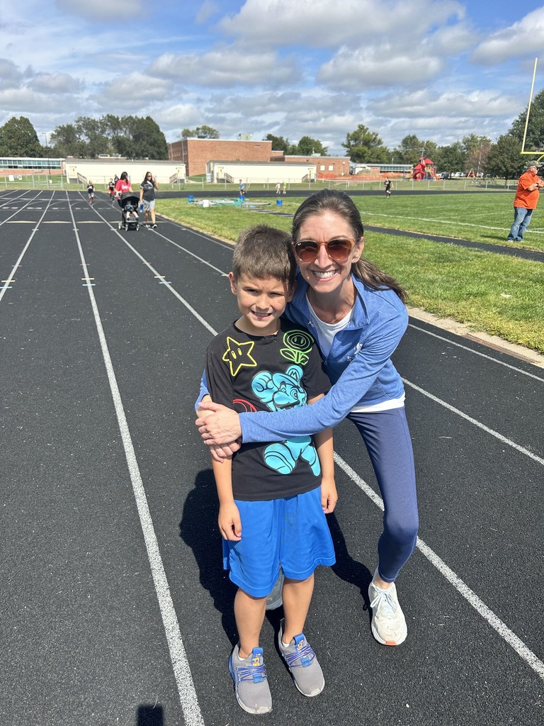 Boy and his mom hugging while smiling on a running track.
