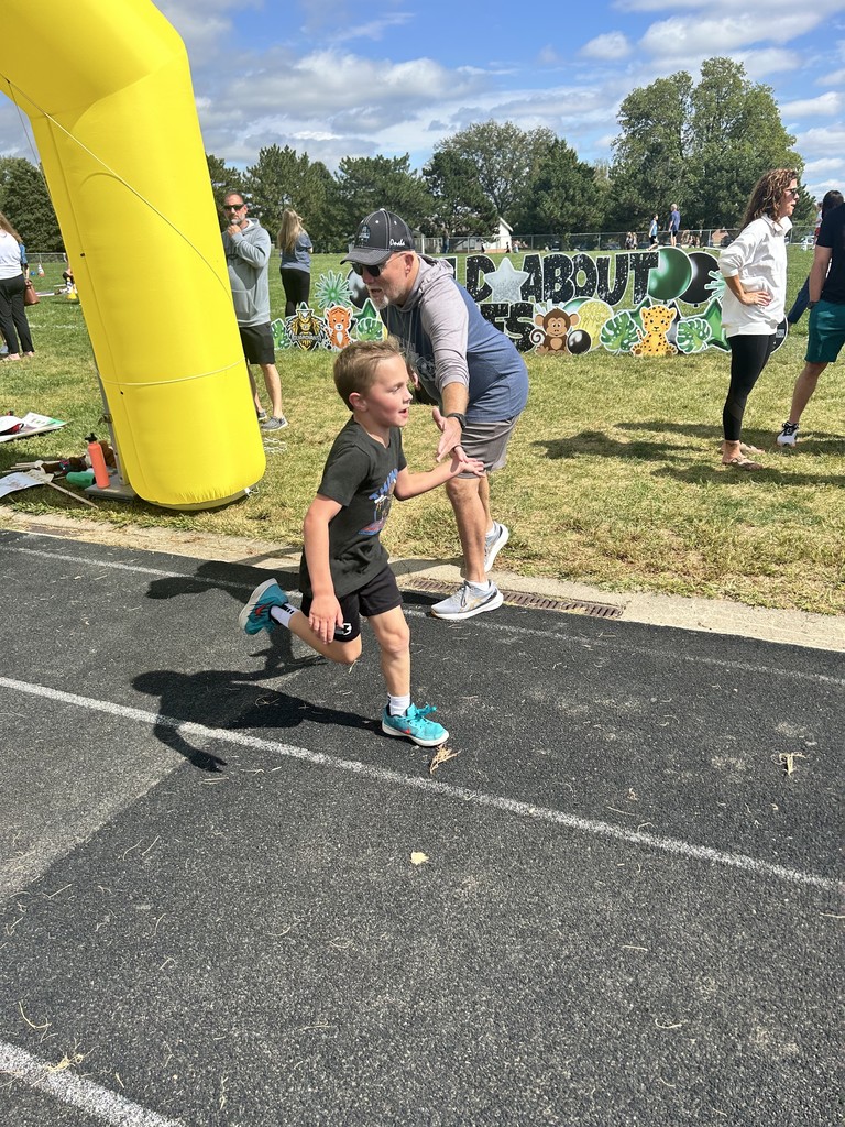 Boy running on a track giving a high five to an adult.