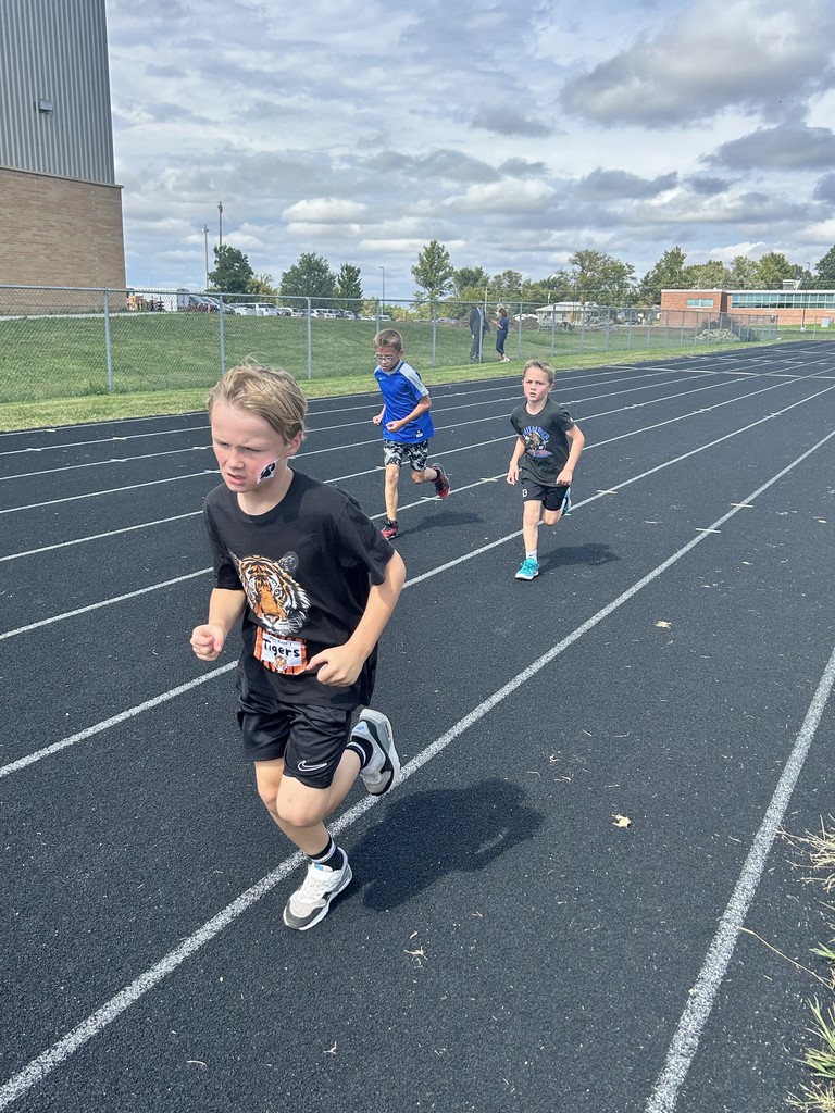 Three boys running on a running track.
