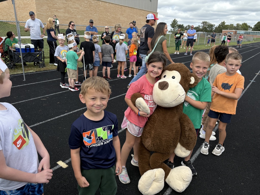 Group of students standing on a running track with one holding a large monkey.