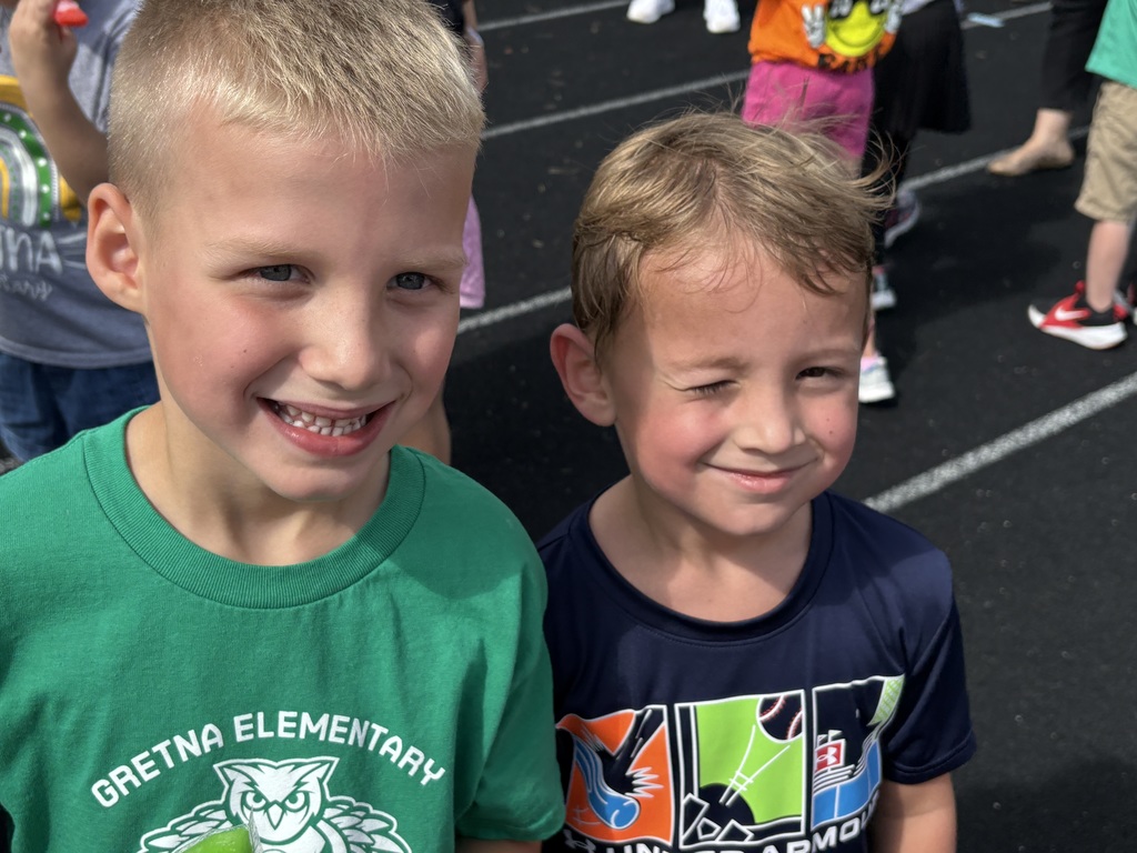 Two boys standing on a running track smiling.