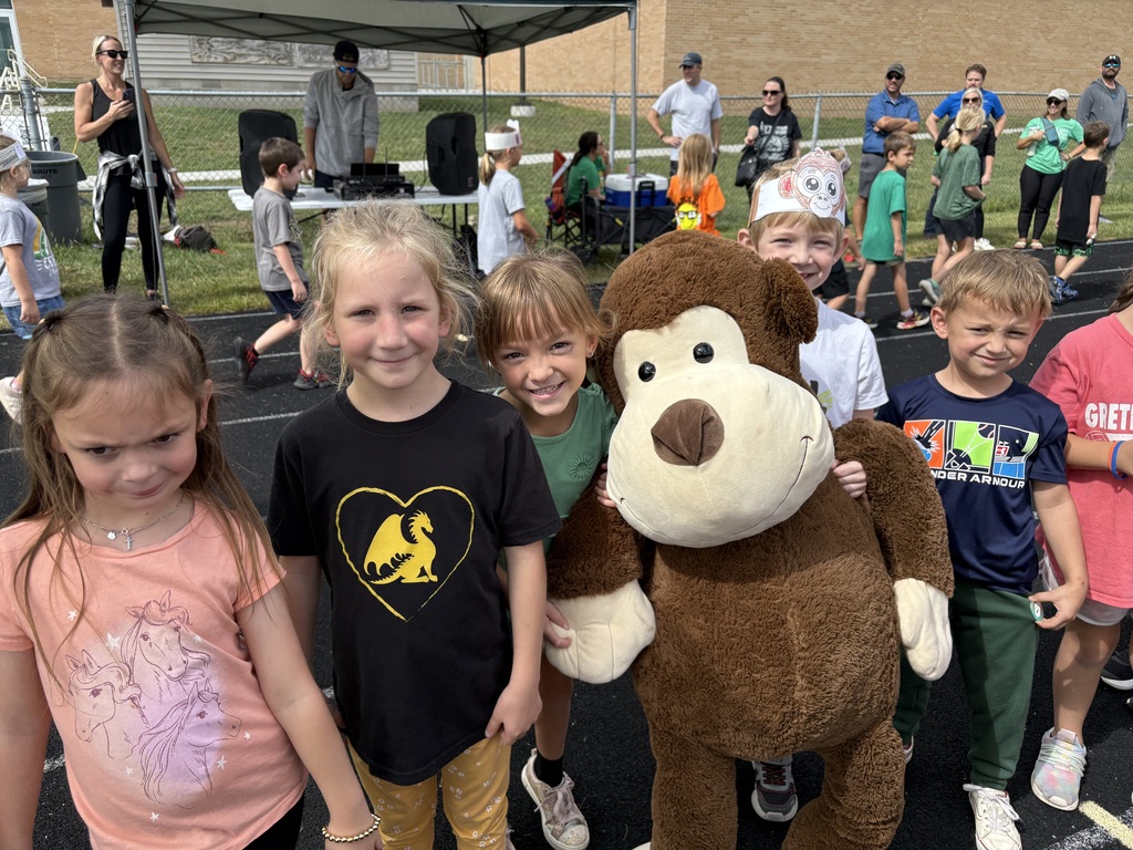 Group of students standing on a running track with one holding a large monkey.