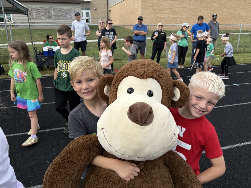 Group of students standing on a running track with two holding a large monkey.