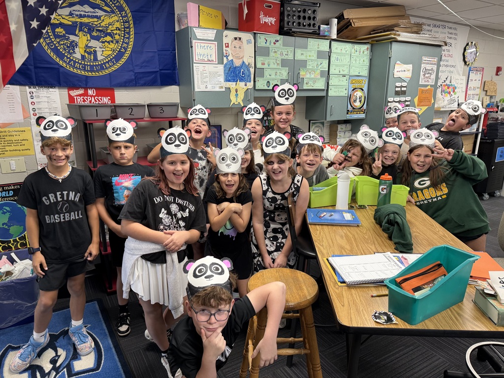 Group of students standing in a classroom with panda paper headbands.