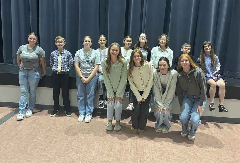 8th grade students who dressed up for sprit week, posing in front of the stage in the cafeteria. 