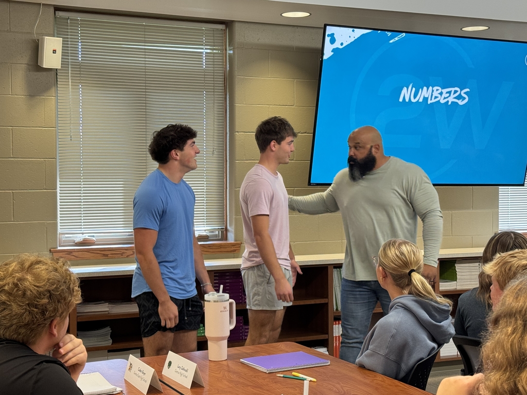 Speaker Steve Mackey talking to two students in front of conference room