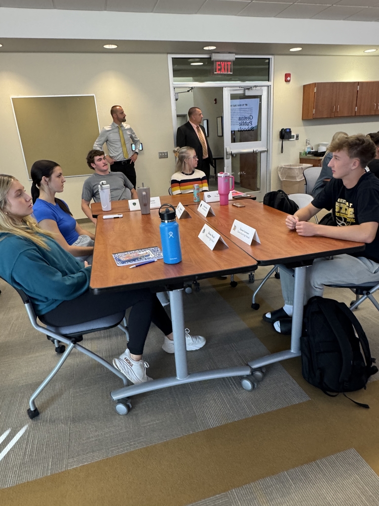 table full of students listening to Steve Mackey present - Superintendent Lightle in background