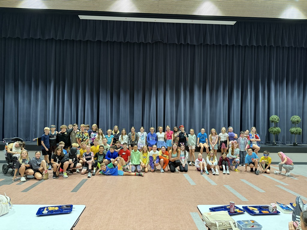 6th grade students who dressed up for sprit week, posing in front of the stage in the cafeteria. 