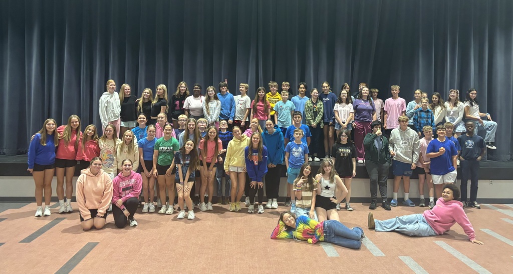 8th grade students who dressed up for sprit week, posing in front of the stage in the cafeteria. 