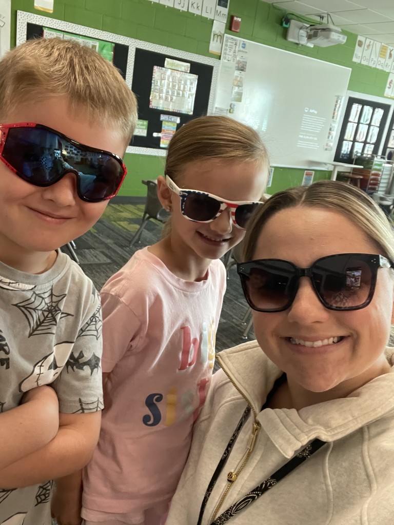 A kindergarten teacher with two students wearing sunglasses taking a selfie.