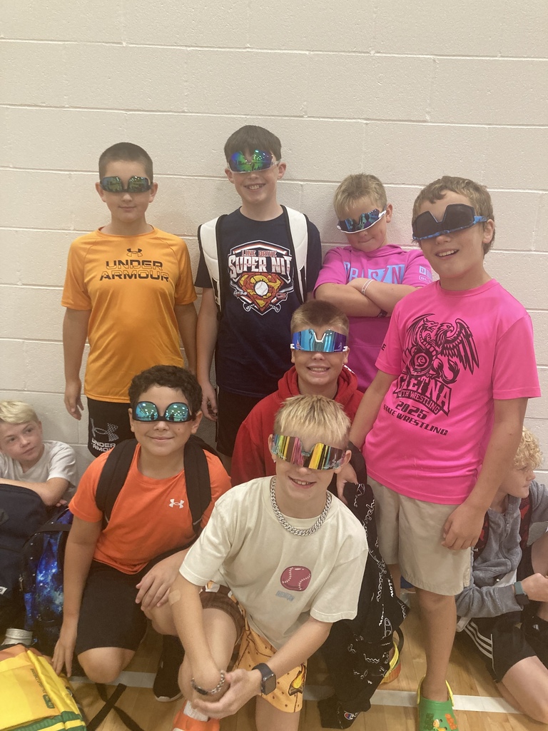 A group of 7 fifth grade boys wearing their sunglasses upside down.