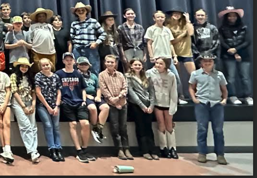 7th grade students who dressed up for sprit week, posing in front of the stage in the cafeteria.
