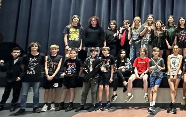 7th grade students who dressed up for sprit week, posing in front of the stage in the cafeteria.