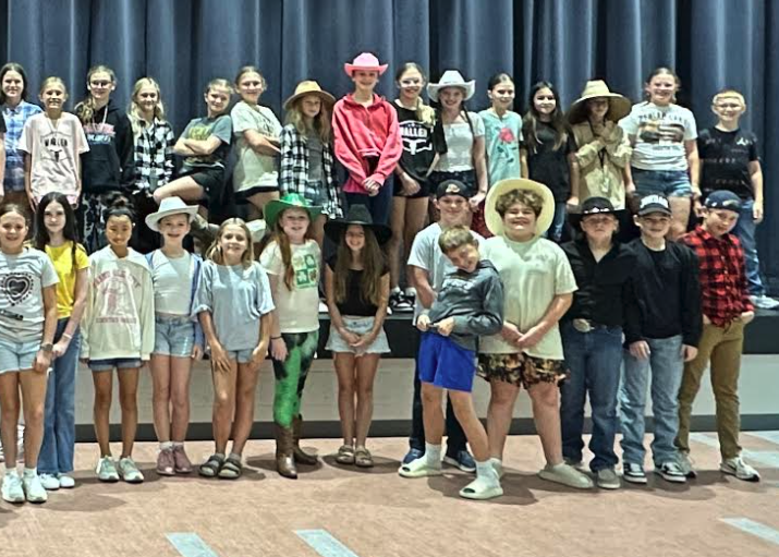 6th grade students who dressed up for sprit week, posing in front of the stage in the cafeteria.
