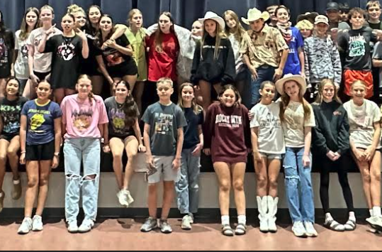 7th grade students who dressed up for sprit week, posing in front of the stage in the cafeteria.