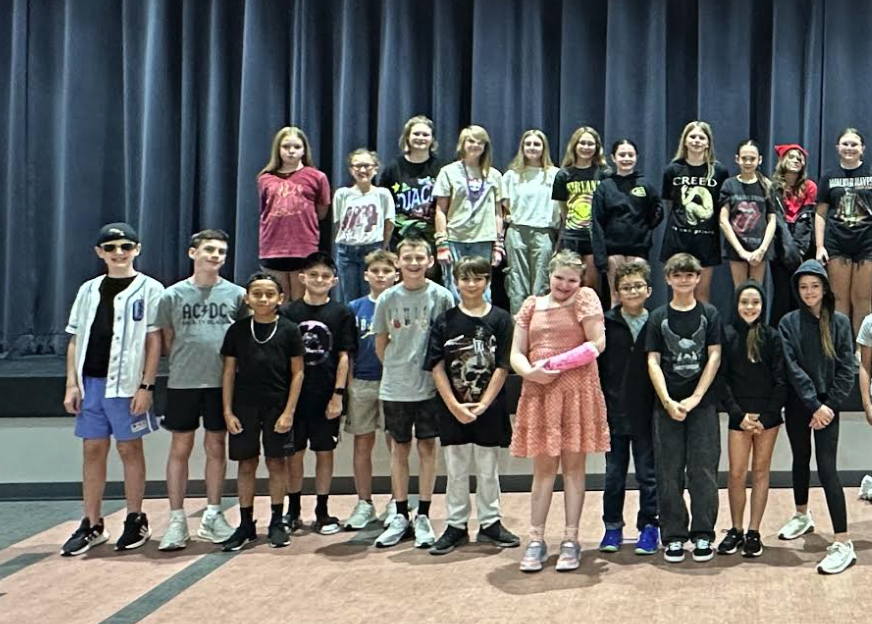 6th grade students who dressed up for sprit week, posing in front of the stage in the cafeteria.