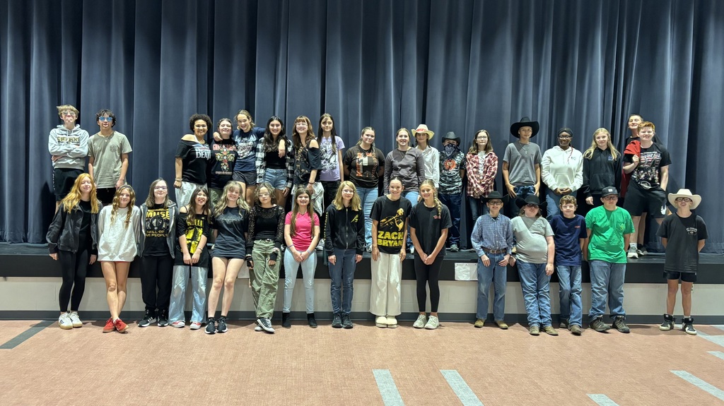 8th grade students who dressed up for sprit week, posing in front of the stage in the cafeteria.
