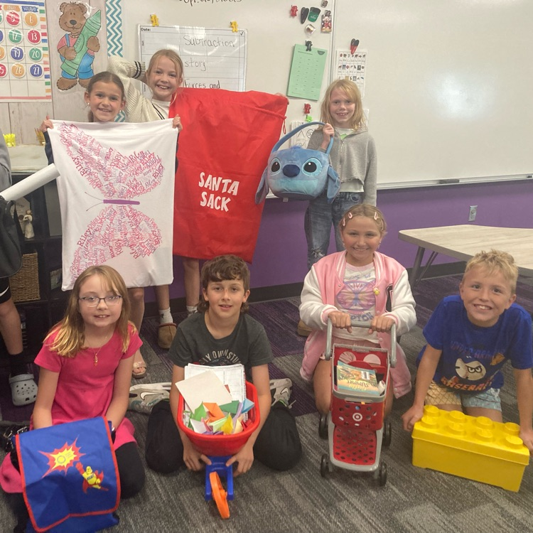 students holding items like pillowcases, toy shopping carts and Lego boxes for their “backpacks"
