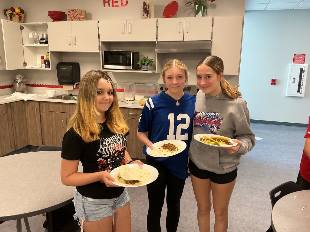 8th grade students holding their tacos on a plate.