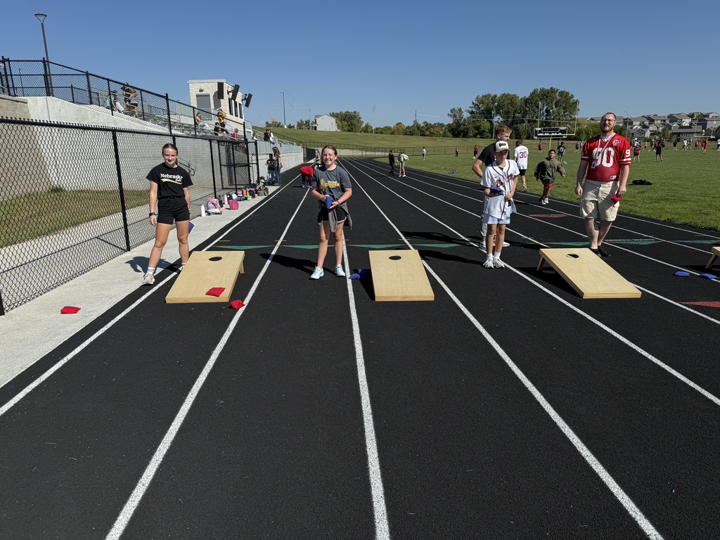 Staff and students playing a game of cornhole on the track.