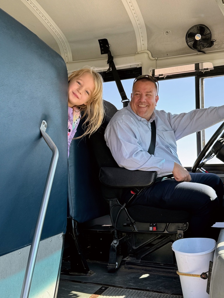 Superintendent Lightle and elementary student smiling on the bus as he gets ready to drive them home