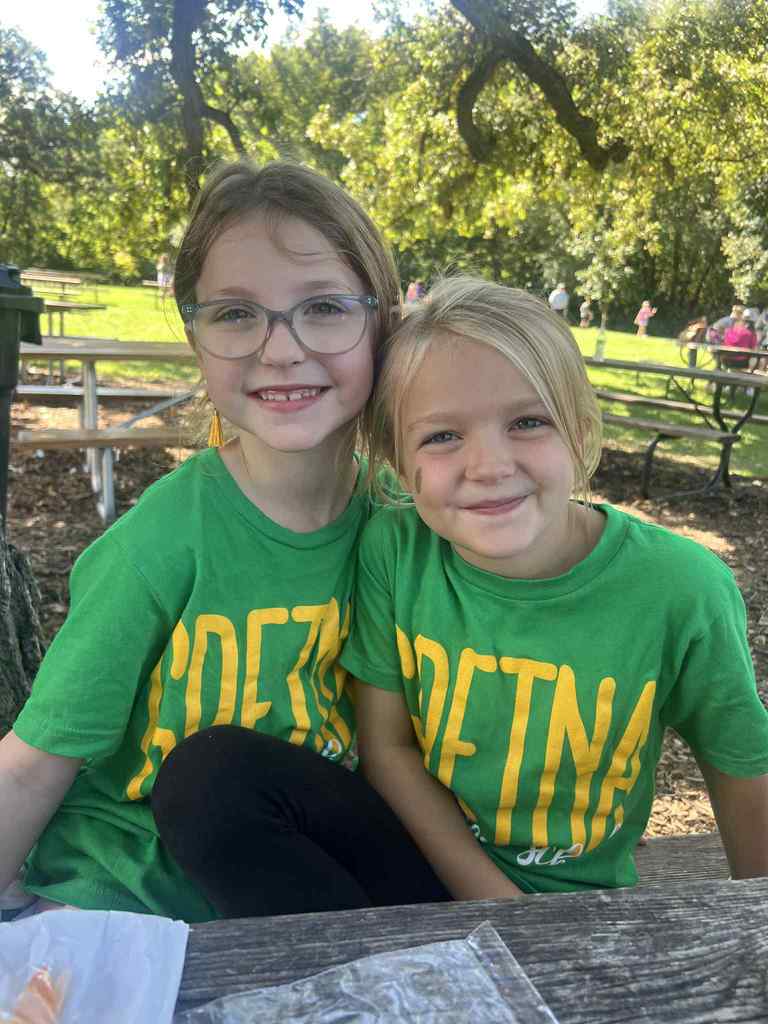 Two girls smiling wearing green t-shirts.