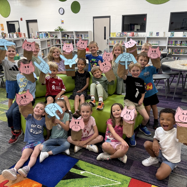 A class of kindergartners holding up Elephant or Piggie puppets. 