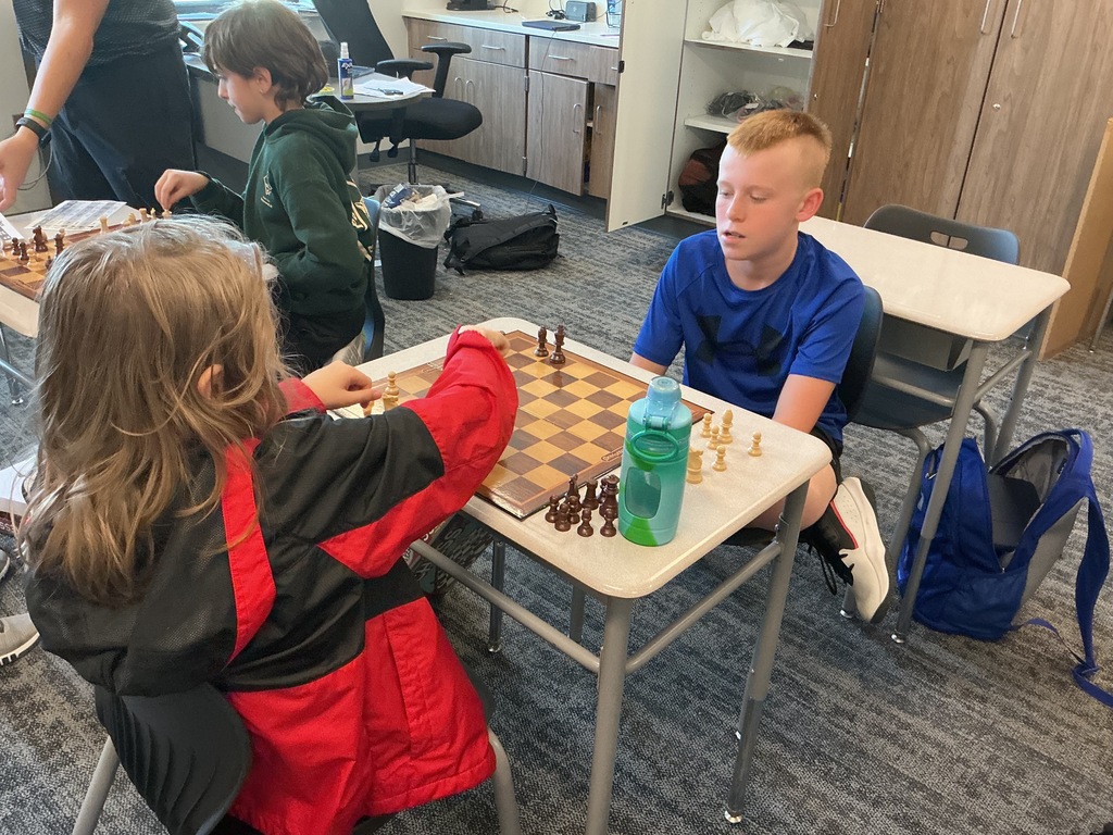 Photo of two students playing chess at a desk.