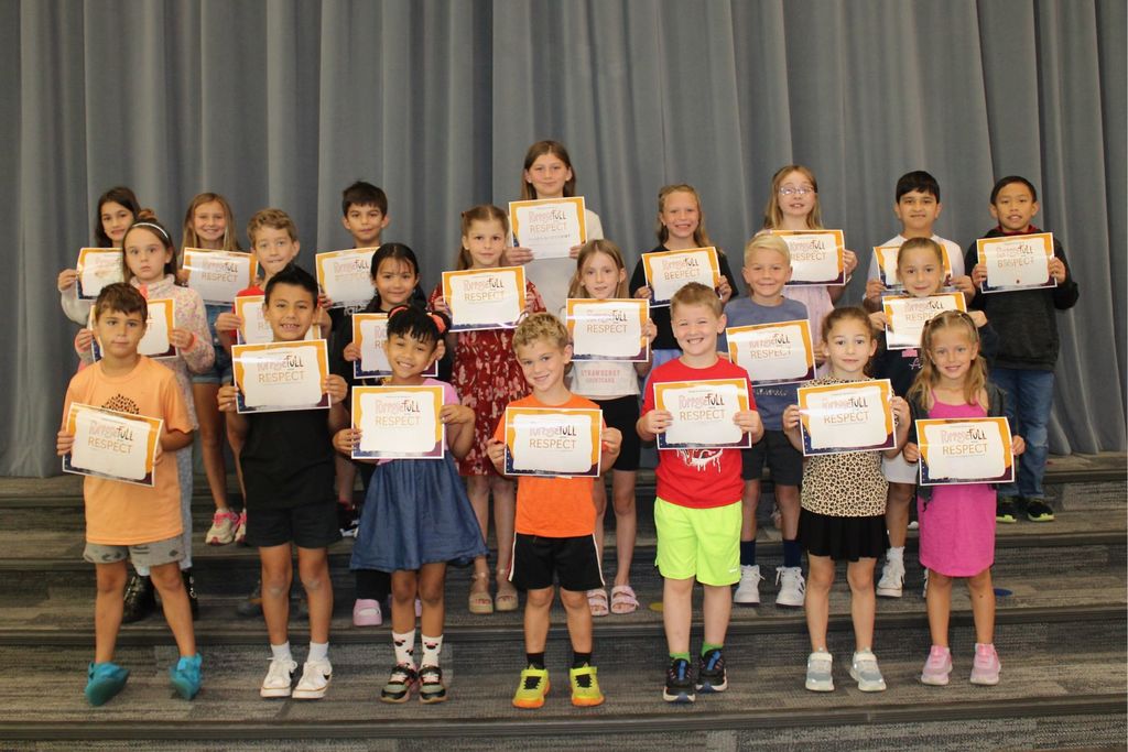 Three rows of students holding their signs for being the Student of the Month who demonstrates Respect