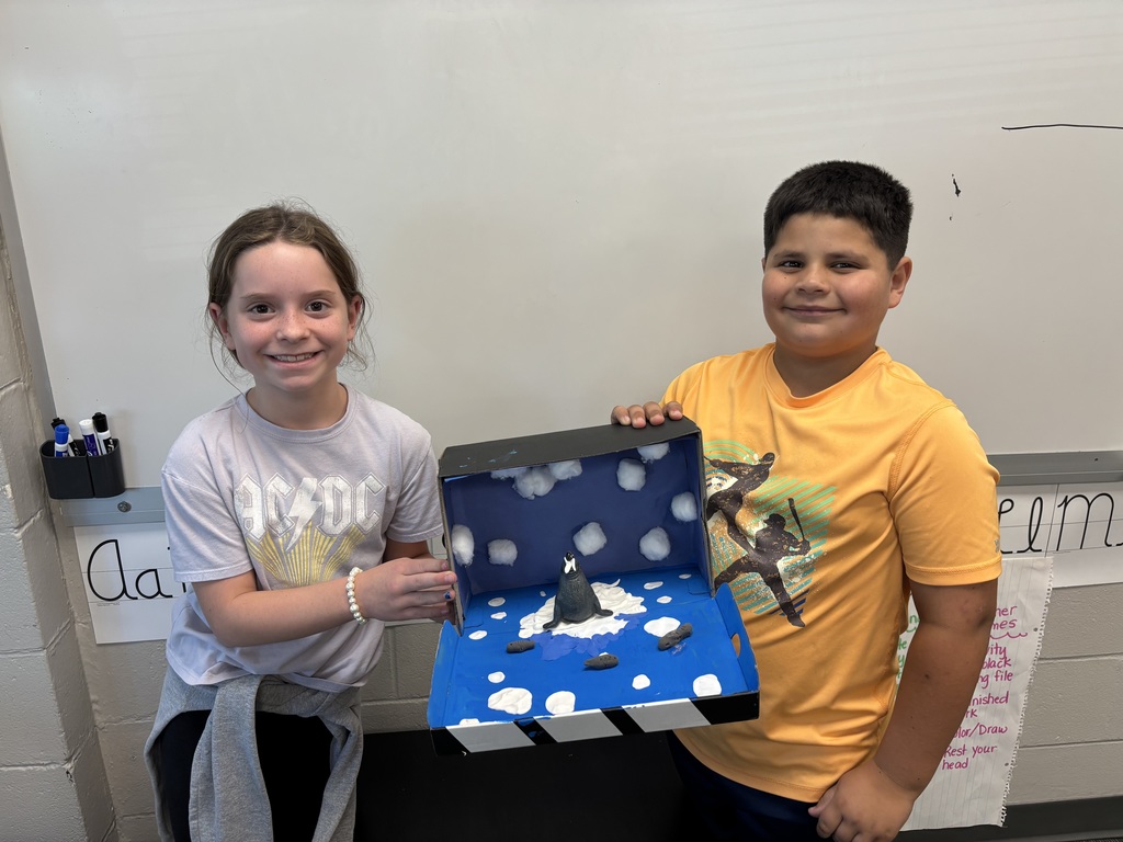 Boy and girl smiling holding a blue shoe box with black and white art material inside.