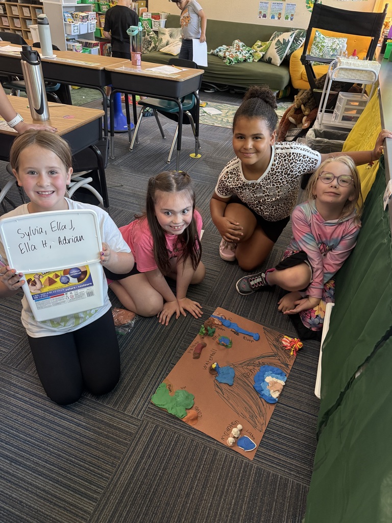 Group of girls sitting on carpet with clay made into animal landforms.