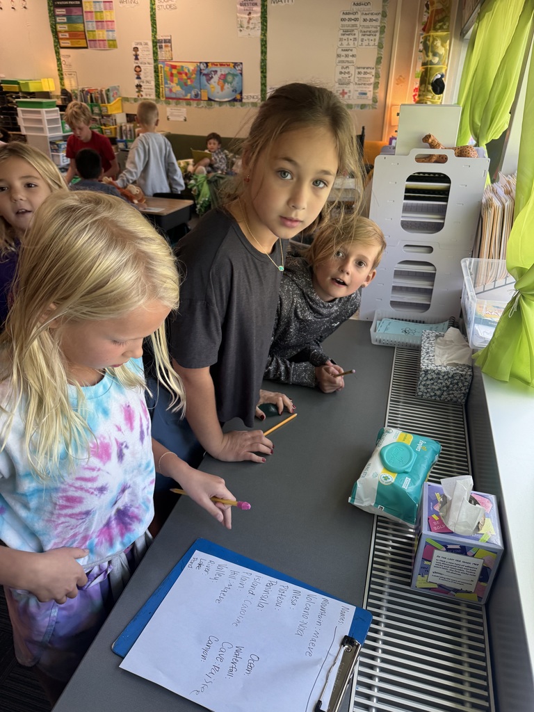 Group of girls standing around a counter whit a clipboard and a piece of paper visible.