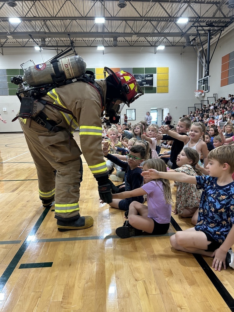 a firefighter giving high fives to students