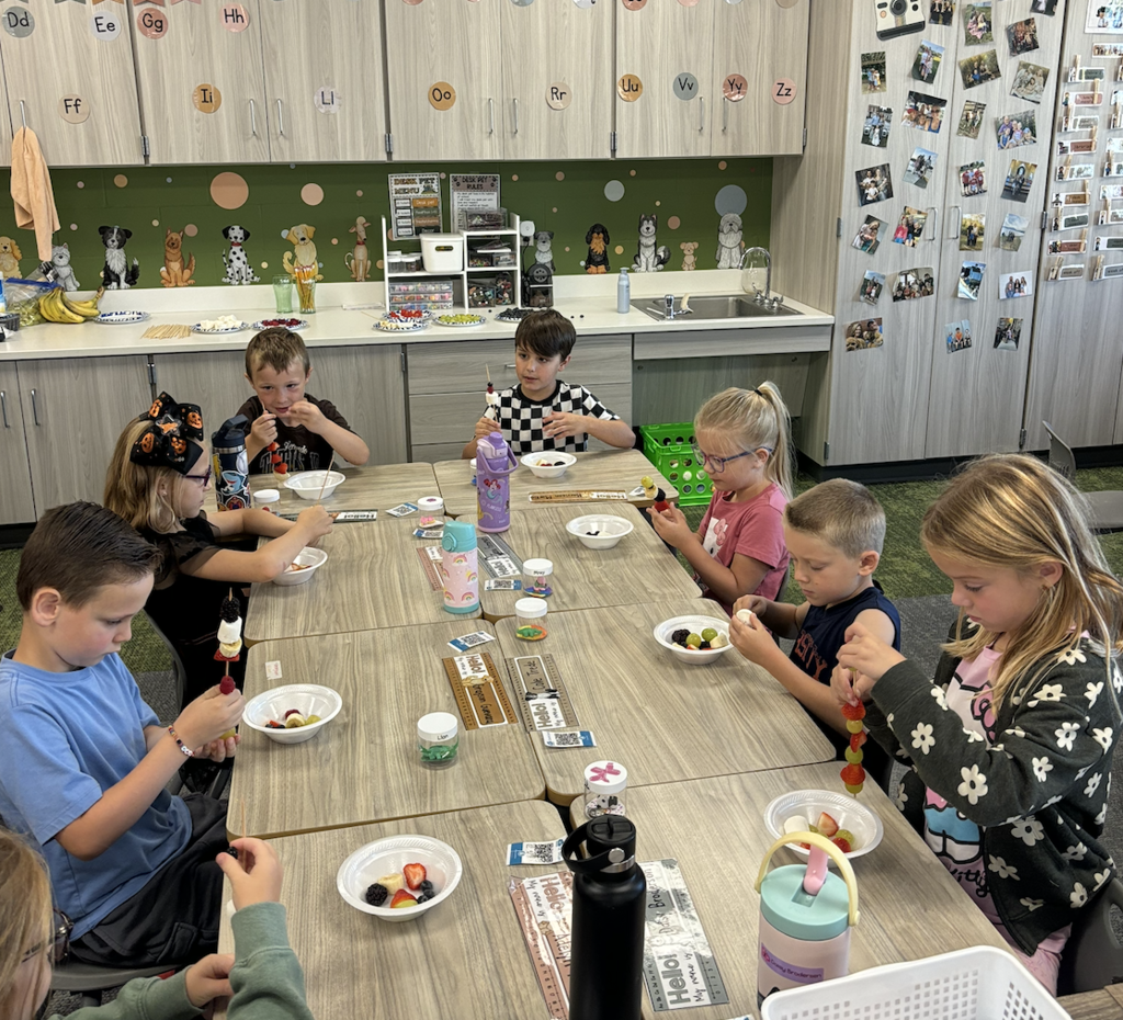 first graders making fruit kebobs