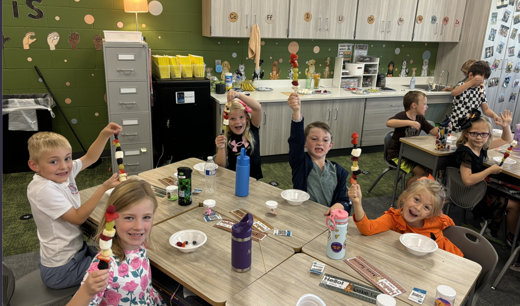 first graders making fruit kebobs