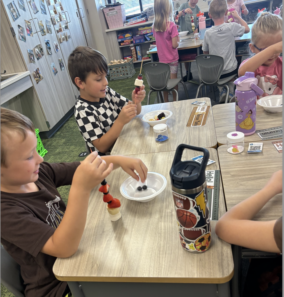 first graders making fruit kebobs