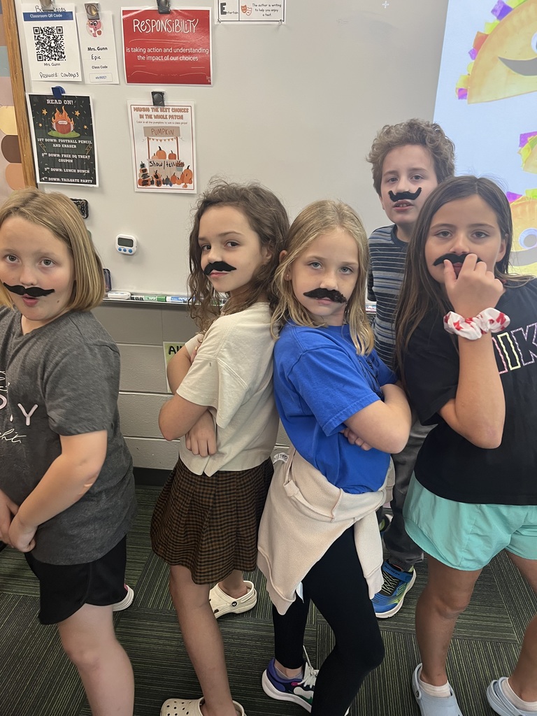 4 girls standing back to back and a boy all wearing fake mustaches.