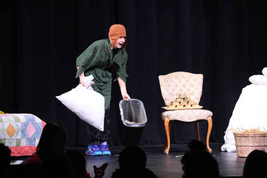 Student in the one act play, holding a trash can and a pillow case. 