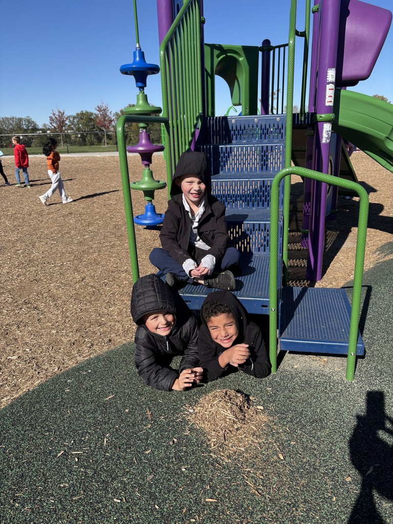 3 first graders sitting on the steps of the slide