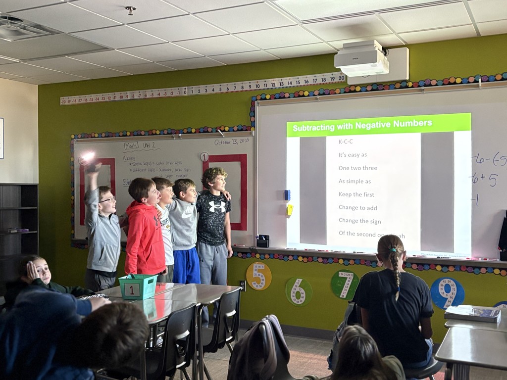 Photo of students looking at lyrics on the whiteboard to sing the song.